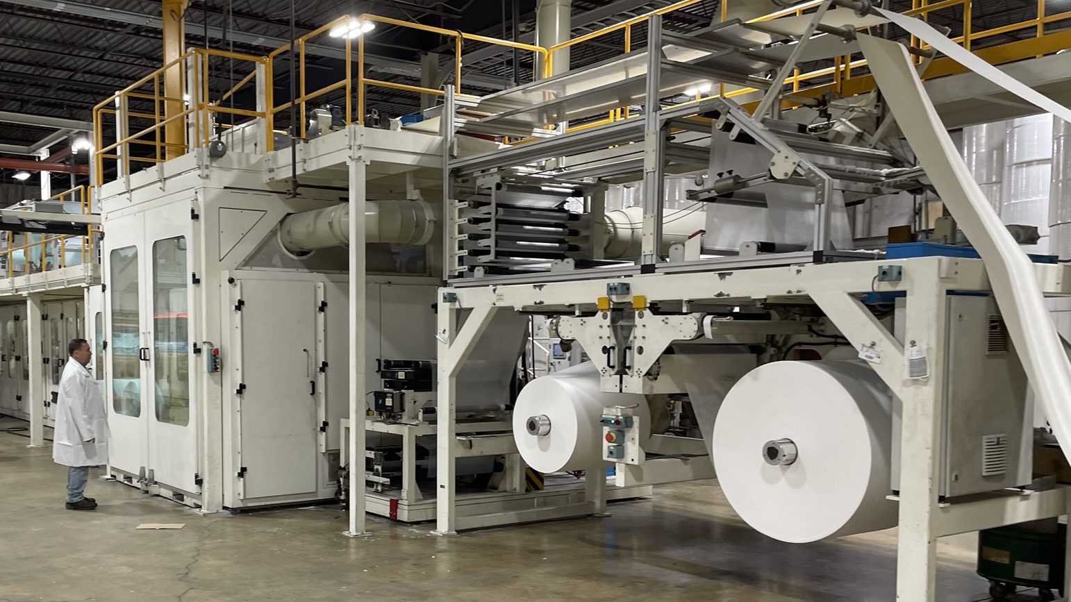 An underpad production line on our plant floor, with large rolls of nonwoven material feeding the machine